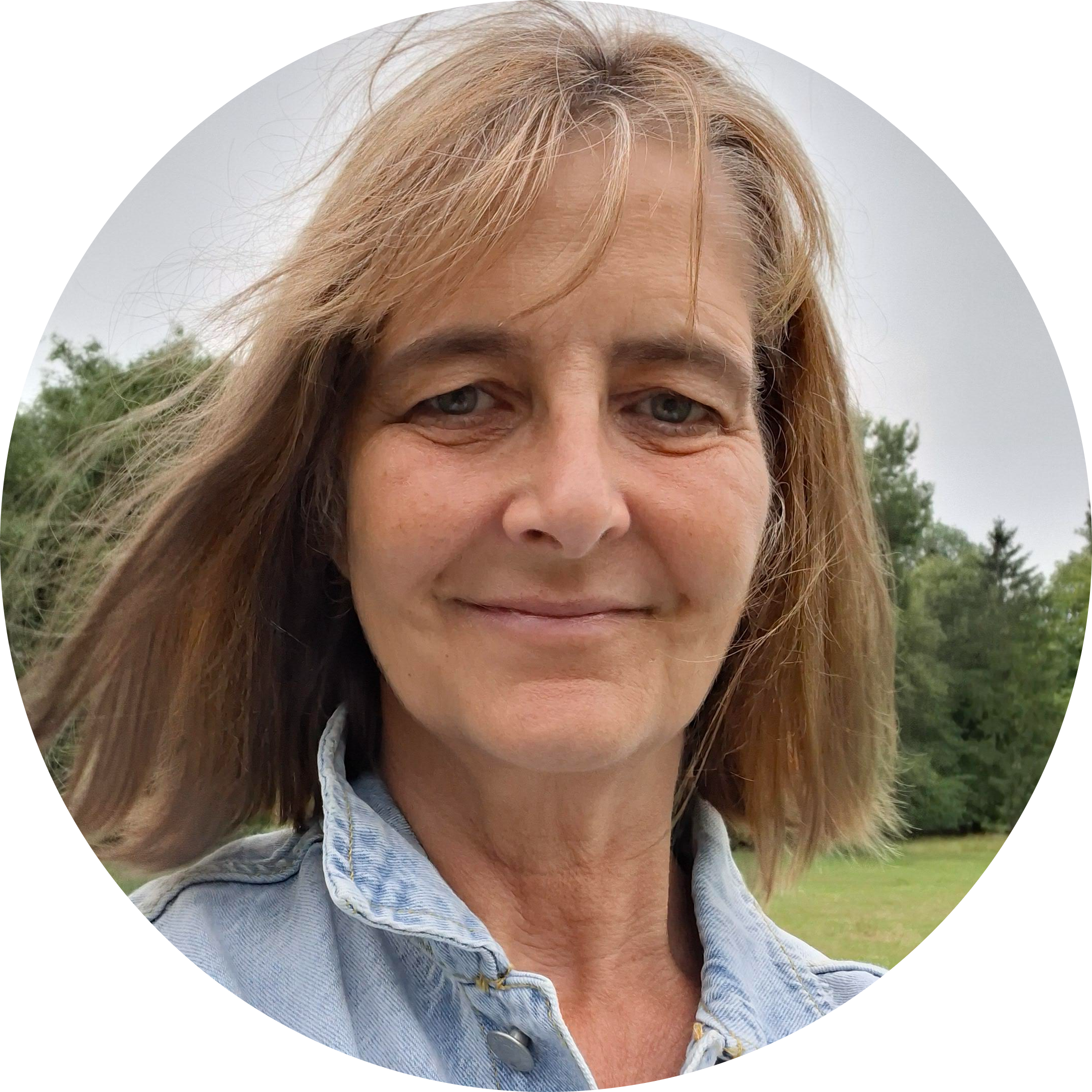 Lady with shoulder length brown hair smiling wearing denim jacket
