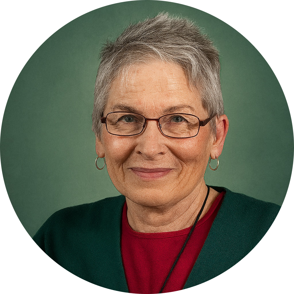 Friendly face, greying hair, short hair style, wearing glasses and loop earrings.