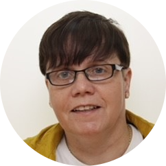 Woman with short brown hair, wearing glasses and a mustard top.